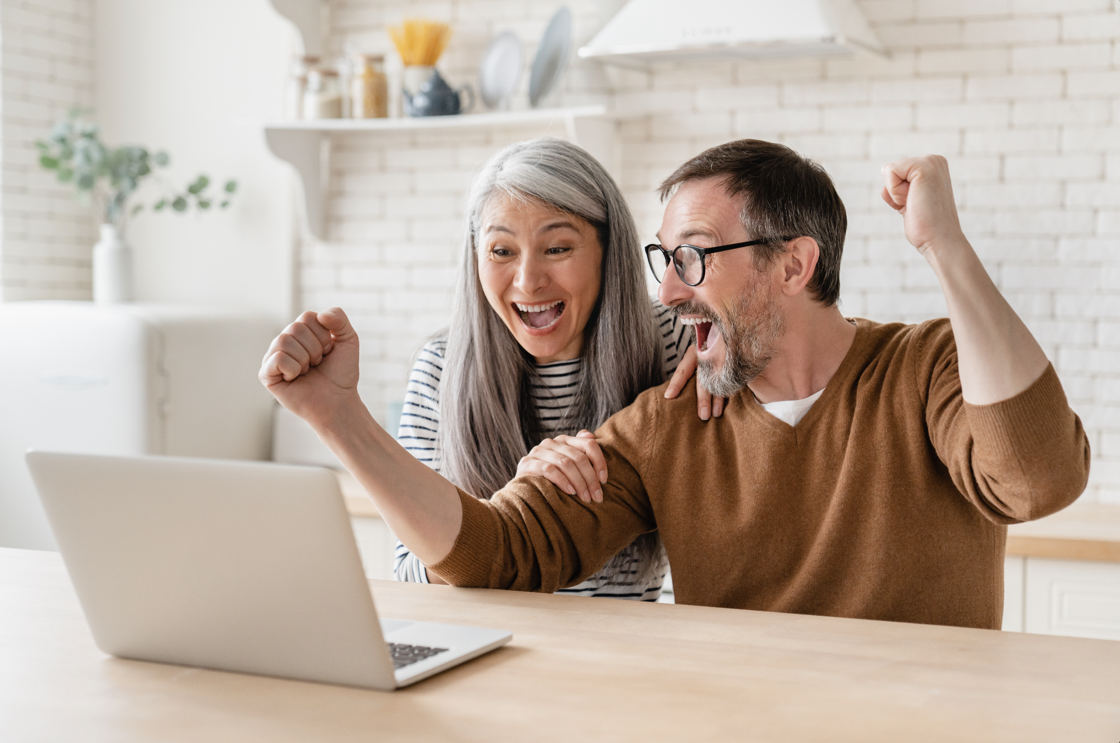 Feliz pareja madura de mediana edad emocionada celebrando su reembolso de impuestos. Imagen de una pareja sonriente que muestra alegría y satisfacción por recibir un reembolso de impuestos.