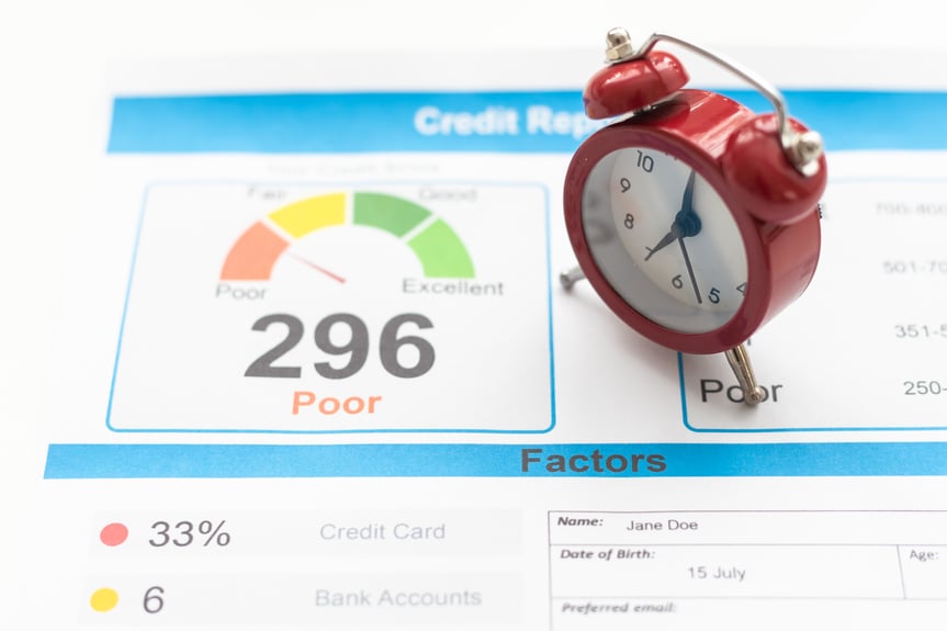 Imagen de un signo que indica que es hora de comprobar su calificación crediticia, ubicado en medio de dos relojes rojos. En el fondo, se pueden ver dinero en efectivo y monedas, que simbolizan la importancia de la salud financiera y la gestión responsable del crédito. La imagen sugiere la necesidad de evaluar y monitorear regularmente la calificación crediticia para tomar decisiones financieras informadas y mantener un buen perfil crediticio.